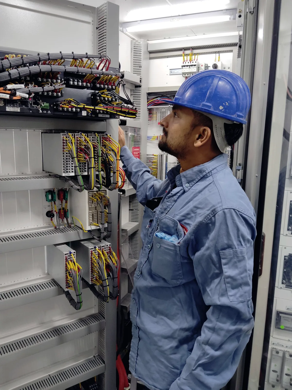 Técnico trabajando dentro de un tablero eléctrico industrial